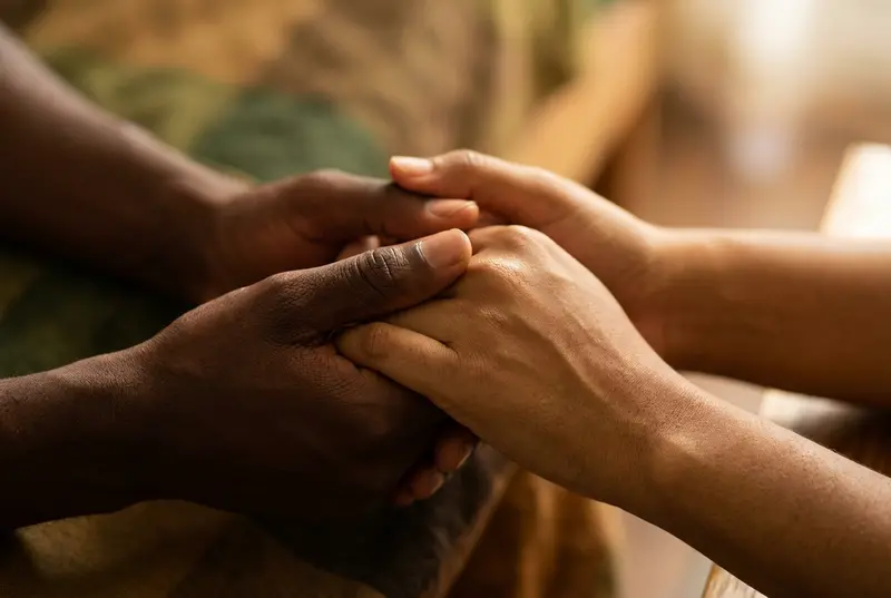 Close-up of two people holding hands tightly showing support and affection.