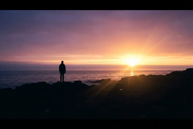 A silhouette of a person watching a beautiful sunrise over the ocean.